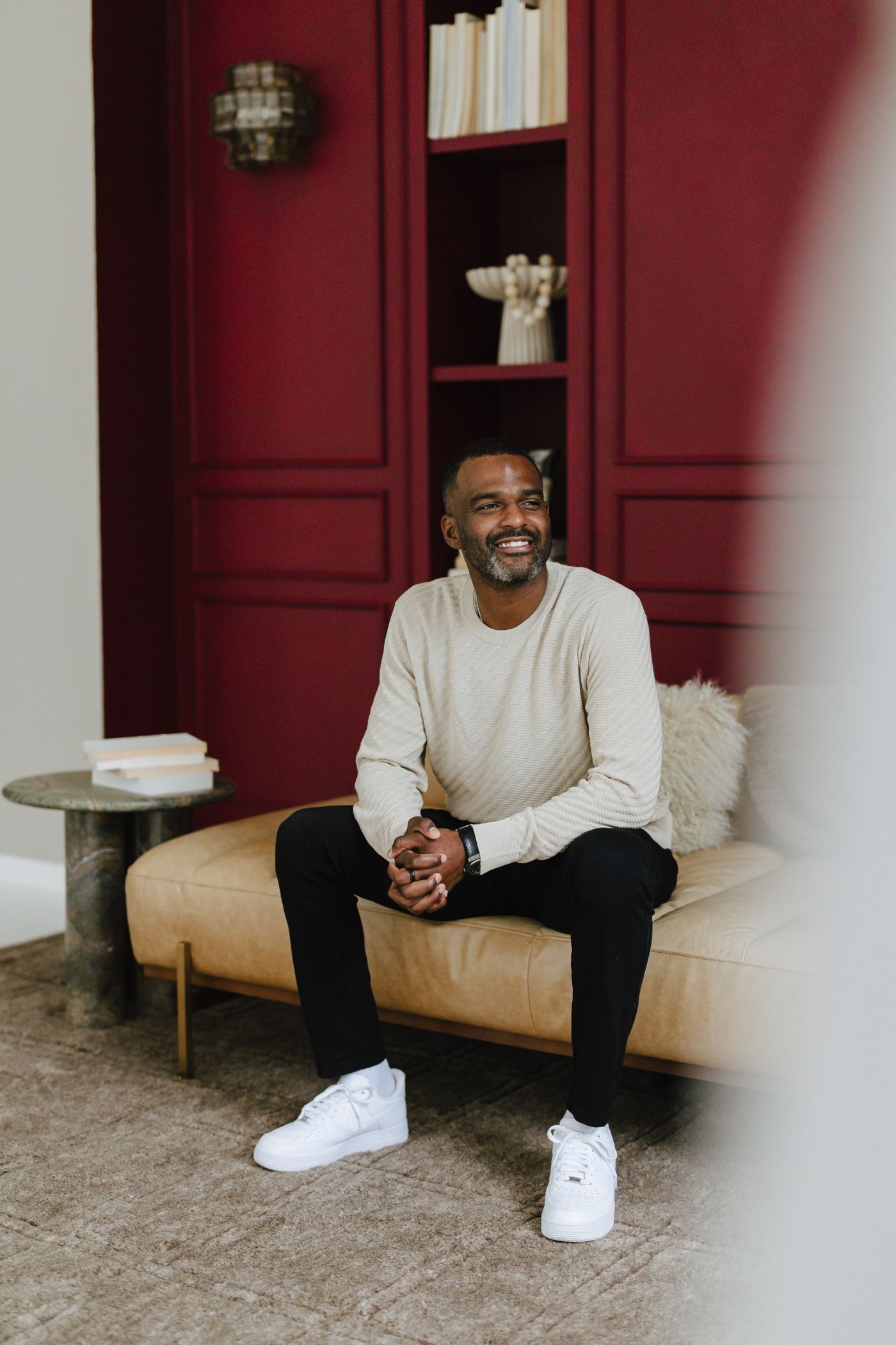 Draymond Washington seated on a leather bench in front of a deep red wall