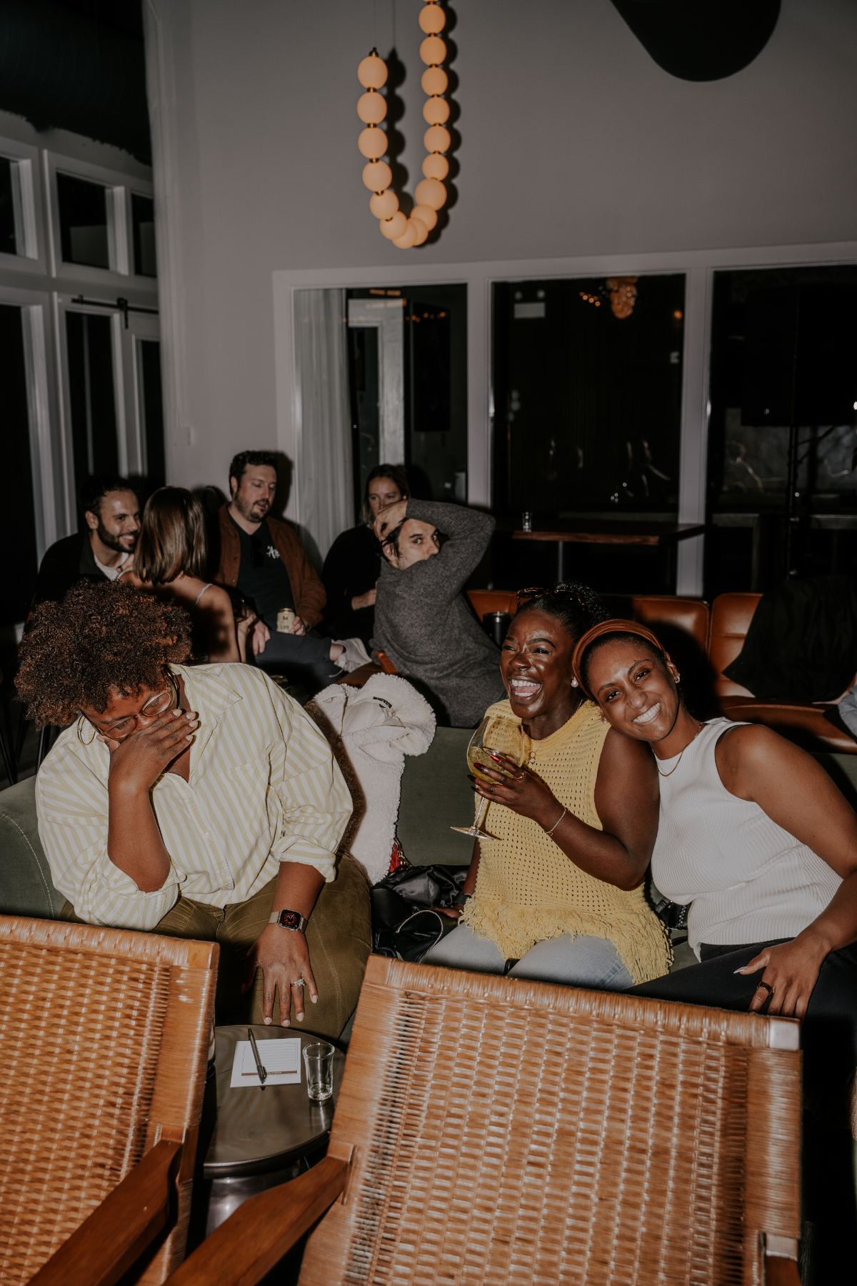 Members laughing together on couches during trivia night at Three Cities Social